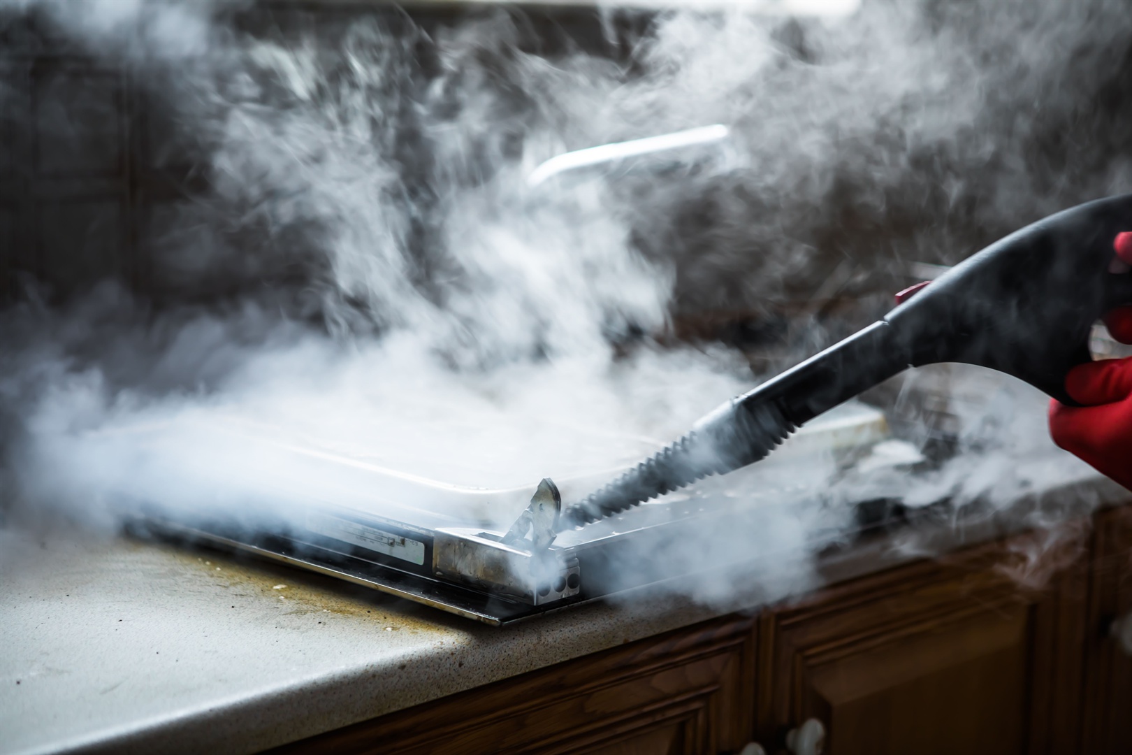 gloved-cleaner-washing-oven-with-steamer-at-home