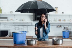 upset-woman-standing-under-umbrella-in-kitchen